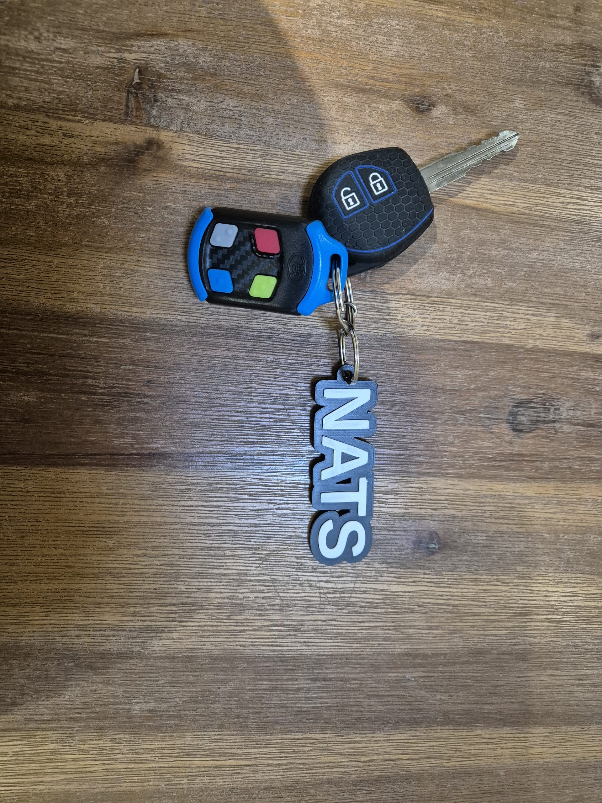 Blue, black and white 3D-printed personalised name keyring attached to car keys