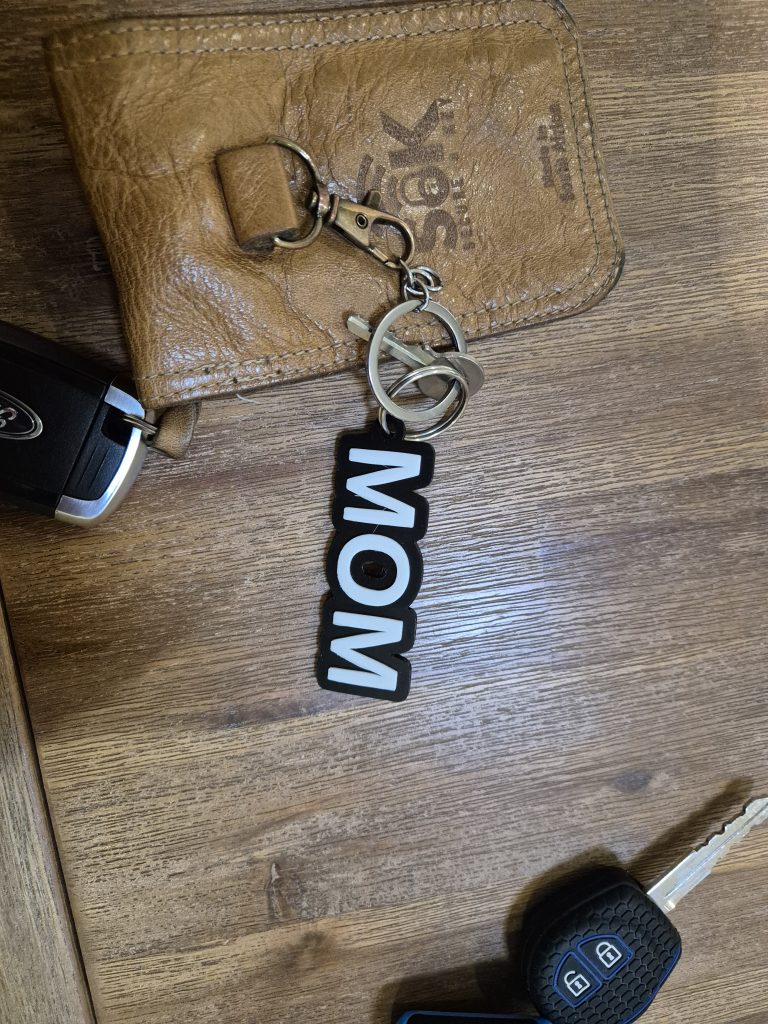 Black and white 3D-printed personalised name keyring attached to car keys
