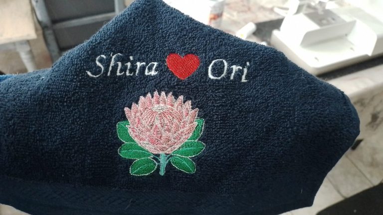 Black fabric embroidered with a protea design and personalised names