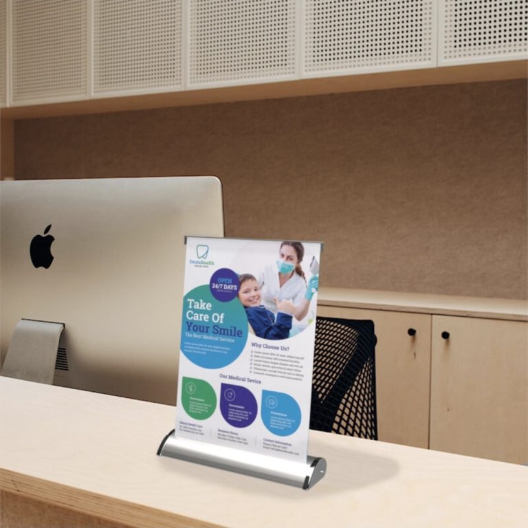 Branded desktop pull-up display beside a computer
