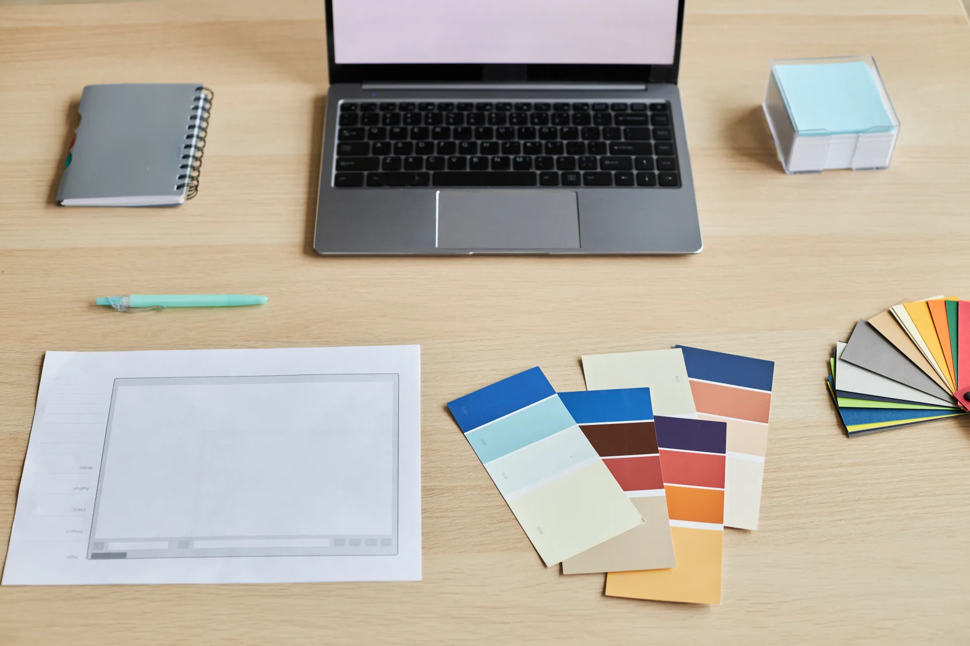 Designer workspace with laptop, blank stationery and colour swatches
