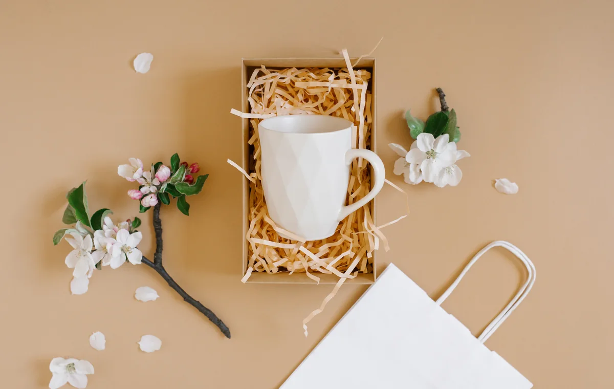 White mug presented in a kraft gift box with paper fill and flowers